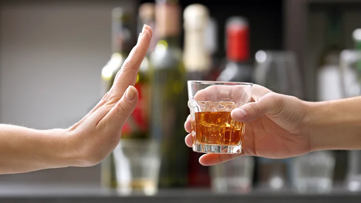 Mão aberta recusando um copo de bebida alcoólica