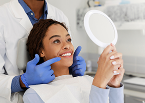 Paciente sorri e vê o sorriso no espelho de um consultório odontológico