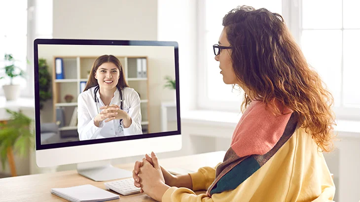 Mulher conversando com a médica em frente ao computador
