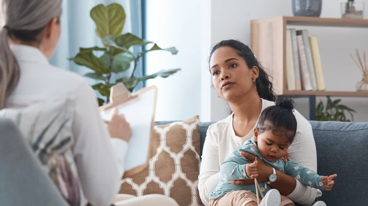 Mãe segurando a criança no colo enquanto conversa com a médica