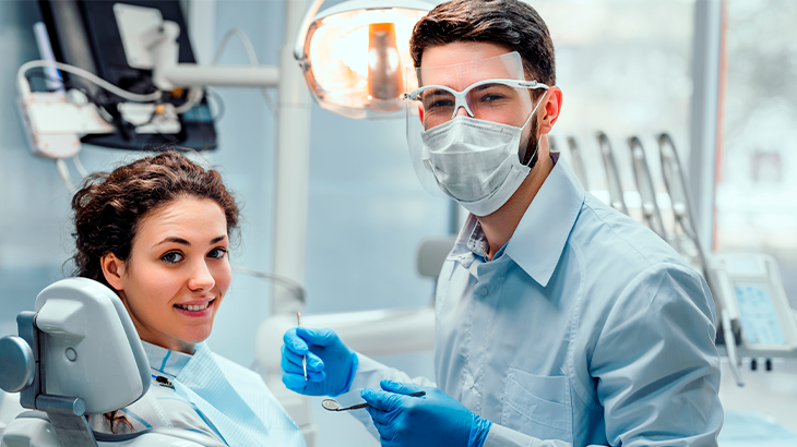Dentista fazendo tratamento dentário na paciente que está deitada