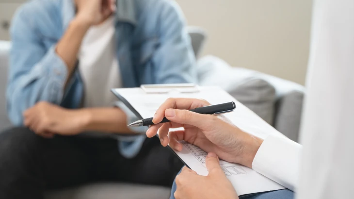 Médico escrevendo enquanto o paciente fala