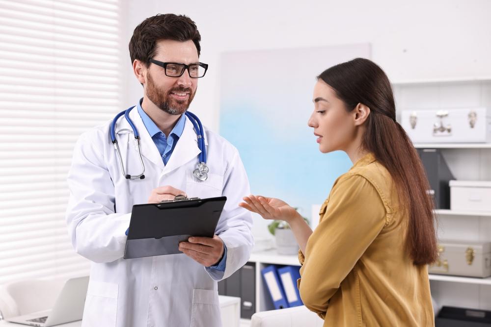 Mulher em consultório conversando com médico, ilustrando a importância de procurar um proctologista quando sintomas de hemorroida são persistentes.