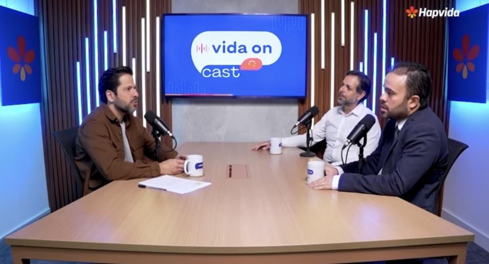 Três pessoas conversando na mesa do podcast.