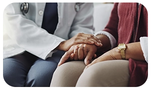 Médica segurando a mão de paciente em gesto de apoio.